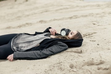 young woman with scarred face wearing respirator and  in urban dark clothes, posing outdoors
