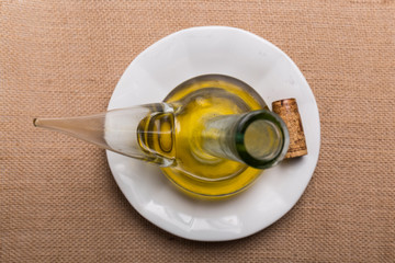 glass container with olive oil, on a brown background, seen from above