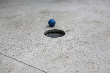 Detail Aufnahme vom Minigolf im Sommer mit einem blauen Ball auf Grauen Untergrund 