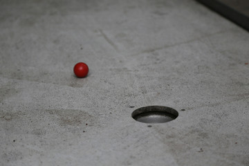 Detail Aufnahme vom Minigolf im Sommer mit einem Roten Ball auf Grauen Untergrund 