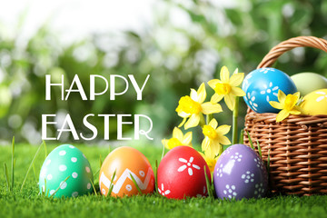 Colorful eggs with daffodil flowers and text Happy Easter on blurred background
