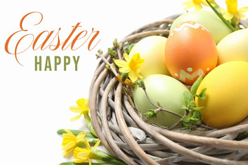 Colorful eggs in decorative nest and text Happy Easter on white background, closeup