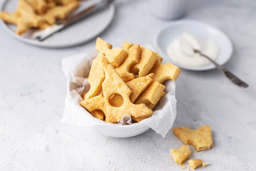 Cheese crackers, salty snack concept. Cookies, piece of cheese on a gray background