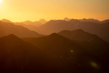 Fototapeten Silhouettes of different layers of mountains with lightbeams during sunset © Patrick