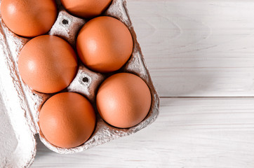 Large brown chicken eggs lie in an eco-friendly cardboard egg tray
