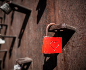 Rusty red love padlock with a heart in the middle.
