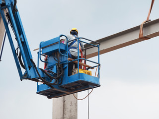 construction worker at construction site using lifting boom machinery