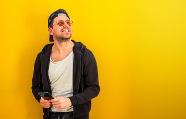 Portrait of a handsome Caucasian man using his cell phone. Yellow background