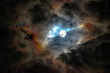 Fototapeta na wymiar Vendée, France: April 2020, the full moon is discovered in a blue and orange cloudy sky.