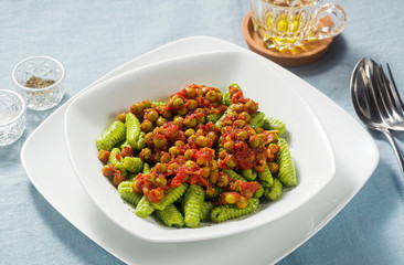 Italian fresh traditional sardinian pasta gnocchi with spinach and green pea tomato sauce. spring pasta for easter holidays.
