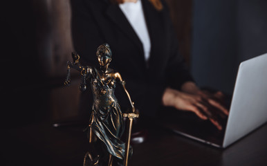 Fototapeta na wymiar Lawyer office. Statue of Justice with scales and lawyer working on a laptop. Legal law, advice and justice concept.