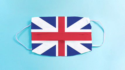 flag of united kingdom on medical facemask isolated on blue background