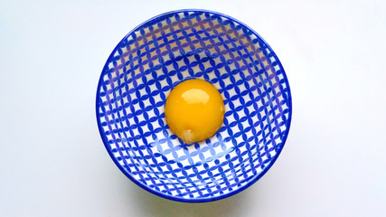 Raw egg yolk in a deep plate with a blue-white pattern