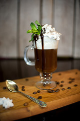 hot chocolate with cream foam is decorated with a sprig of mint in a transparent glass on a dark table