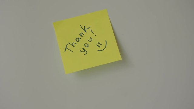 Sticky note Thank you being sticked to white surface