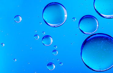 Blue oil drops in water. Bubbles of different sizes on blue abstract background