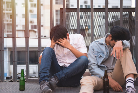 two men drung and sit on street together