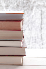 Book stack on wood desk and blurred bookshelf in the library room, education background