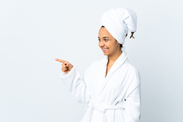Young woman in bathrobe over isolated white background pointing finger to the side and presenting a product