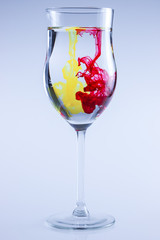 Color drops splash in water. Wine glass isolated.