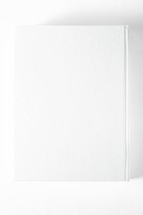 Mockup of closed blank square book at white textured paper background