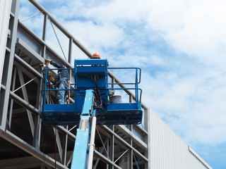 construction worker at construction site using lifting boom machinery