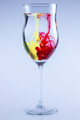 Color drops splash in water. Wine glass isolated.