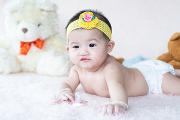Cute little baby lying happy holding nipple soother in hand.Newborn on softness blanket holding  pacifier in hand.Infant tiny hand in the bed,holding pacifier.Baby development concept.