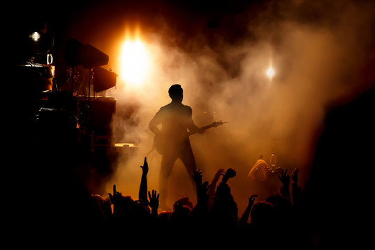 Silhouette of the guitarist on stage over the fans.