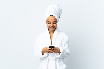 Young woman in bathrobe over isolated white background sending a message with the mobile