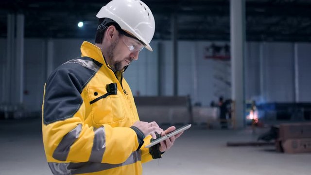Follow footage of employees male warehouse worker engineer in hard hat working. walking through logistics center warehouse factory construction site logistics architect businessman man builder indoors