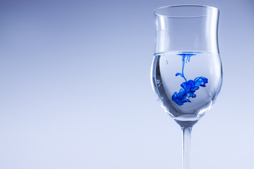 Blue liquid splash in water. Wine glass isolated.