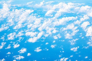 Fototapeta na wymiar Beautiful clouds top view on a background of blue sky from the porthole of an airplane at altitude.
