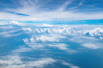 Naklejka na ściany i meble Beautiful clouds top view on a background of blue sky from the porthole of an airplane at altitude.