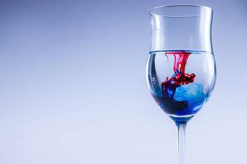 Blue and red color ink in glass with water. Food color splash, motion.