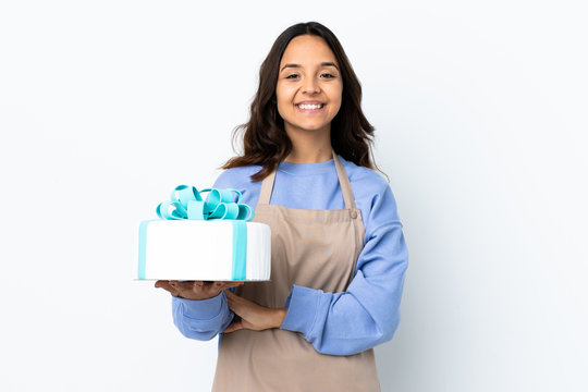 Pastry chef holding a big cake over isolated white background keeping the arms crossed in frontal position