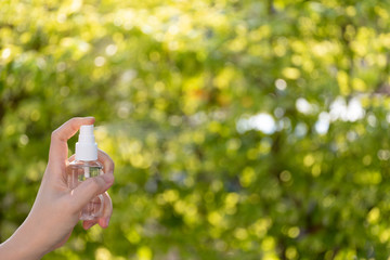 Hand of Asian woman applying the alcohol spray with greenery background. Closed up alcohol spray. Killing the virus.