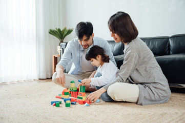 Mom and Dad and daughter at home building blocks