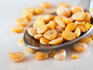 Dried peas in a spoon on white background