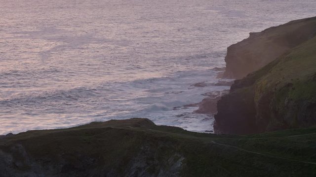 Waves roll in and break along cliff at sunset in Cornwall, England.
(Shot on Arri Alexa Mini LF)