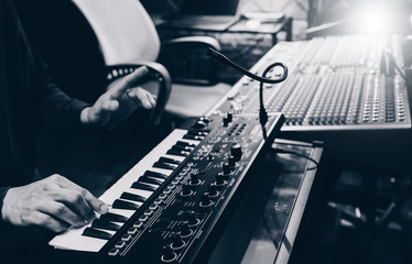 musician hands playing keyboard synthesizer for recording in home recording studio