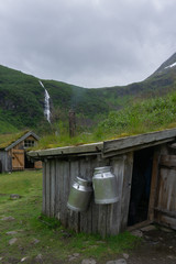 Milchkannen aufgehängt an einer Hütte in einem traditionellen norwegischen Dorf im Geiranger Fjord