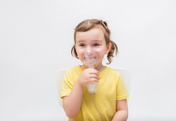 The baby is sick, the sweet girl breathes through the inhaler. Children's diseases.On white background with copy space