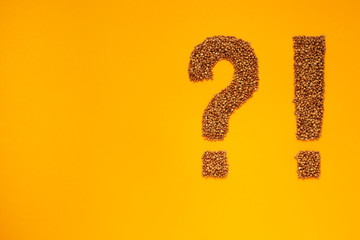 Exclamation point and question mark shapes of buckwheat groat on orange background.
