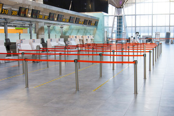 Empty passenger terminal at the airport. Paths limited and separated by a red flight to the check-in desk.