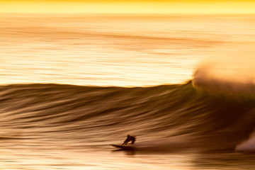 speed blur of a surfer riding a wave at sunset