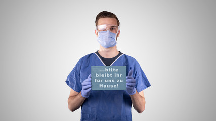 Arzt oder Pfleger mit Mundschutz und Schutzbrille und Hinweisschild vor grauem Hintergrund