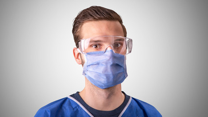 Arzt oder Pfleger mit Mundschutz und Schutzbrille vor grauem Hintergrund