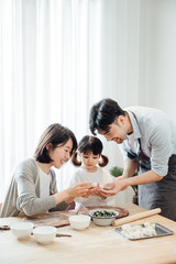 Fototapeta premium Mom and Dad and daughter at home dumplings