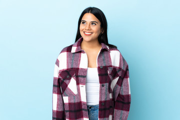 Young latin woman woman isolated on blue background thinking an idea while looking up